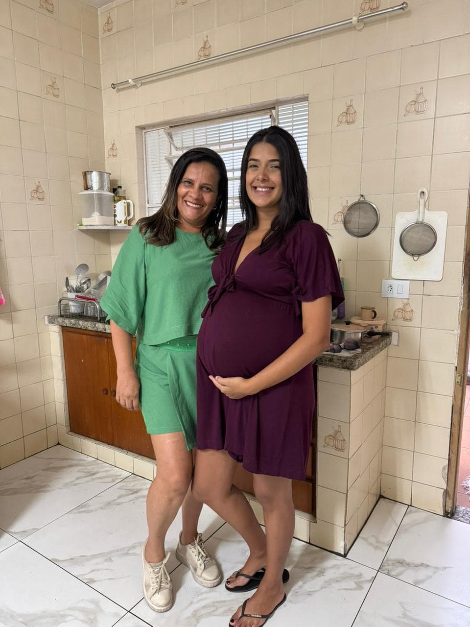 Duas alunas com as peças que costuraram, em casa